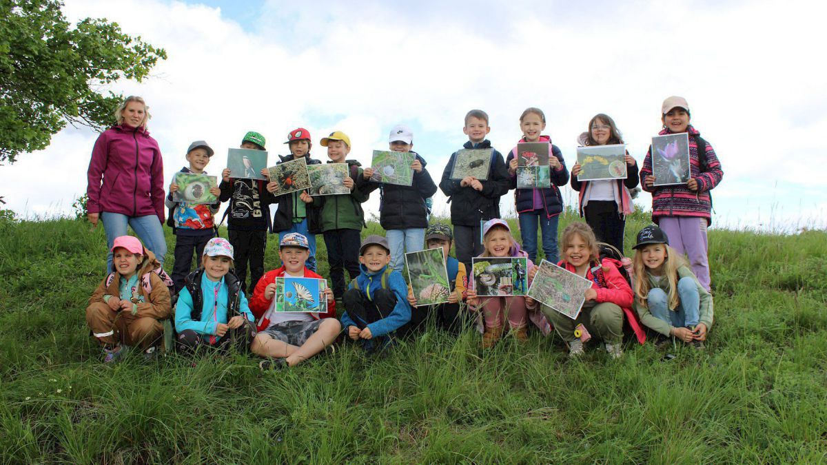 Kinder sitzen und stehen auf einer Wiese.