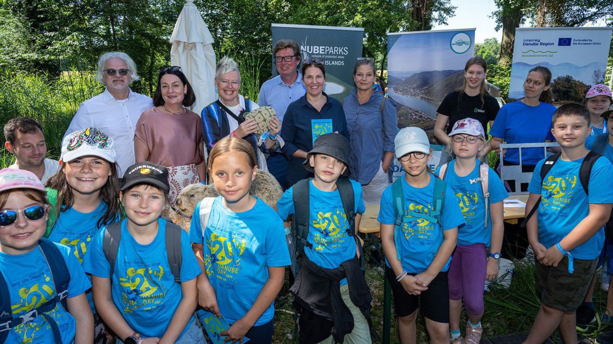 Kinder mit blauen T-Shirts stehen im Auwald cor Rollups